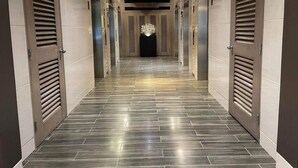 A hallway with a modern design, featuring a patterned floor and metallic doors with louvered panels. -  Shore Residences MOA by darpm (Pasay)