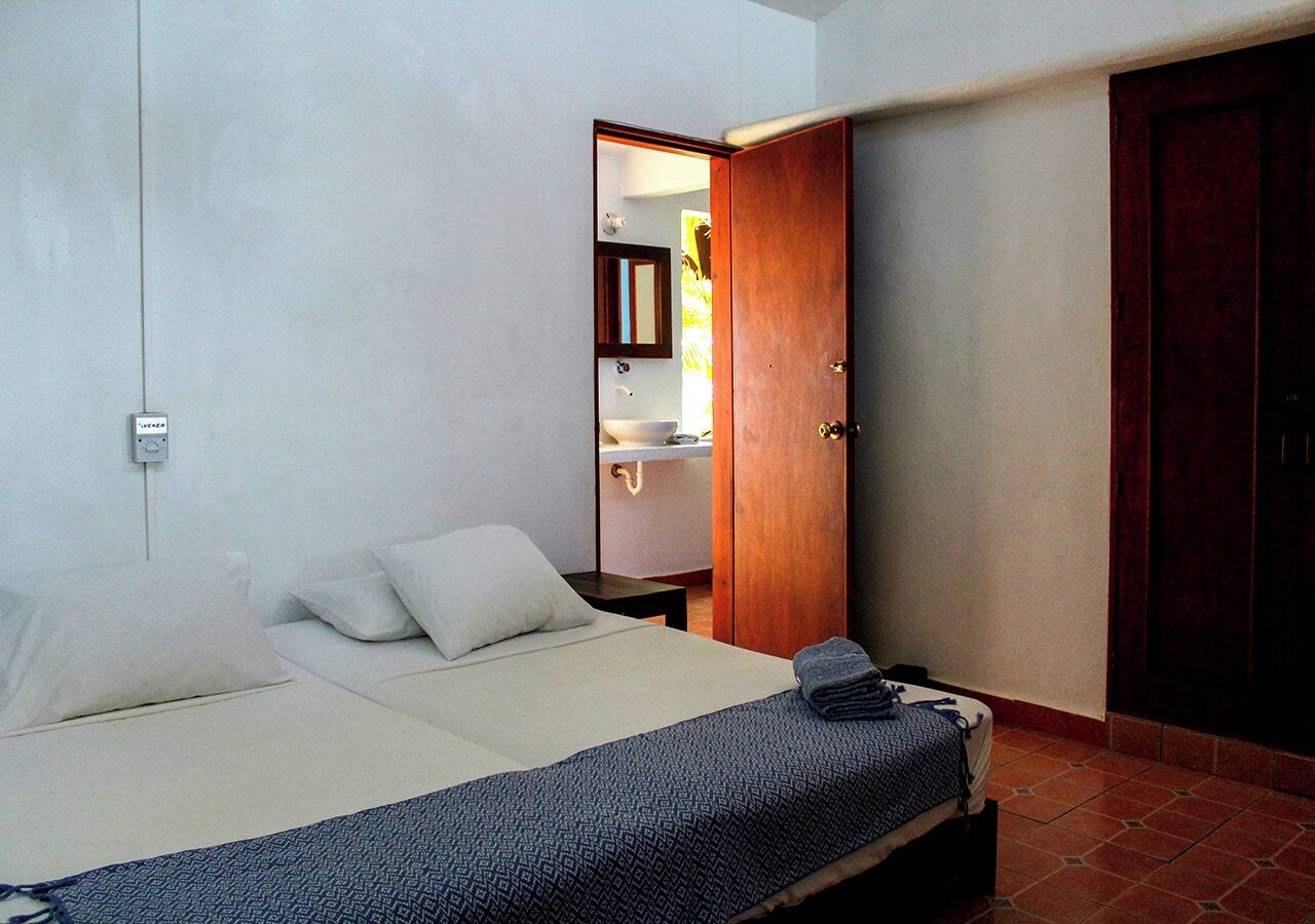 A bedroom with a bed, a bedside table, a mirror, and a wardrobe.