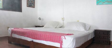 Habitación con cama individual, estructura de madera, ropa de cama blanca y una colcha roja.
