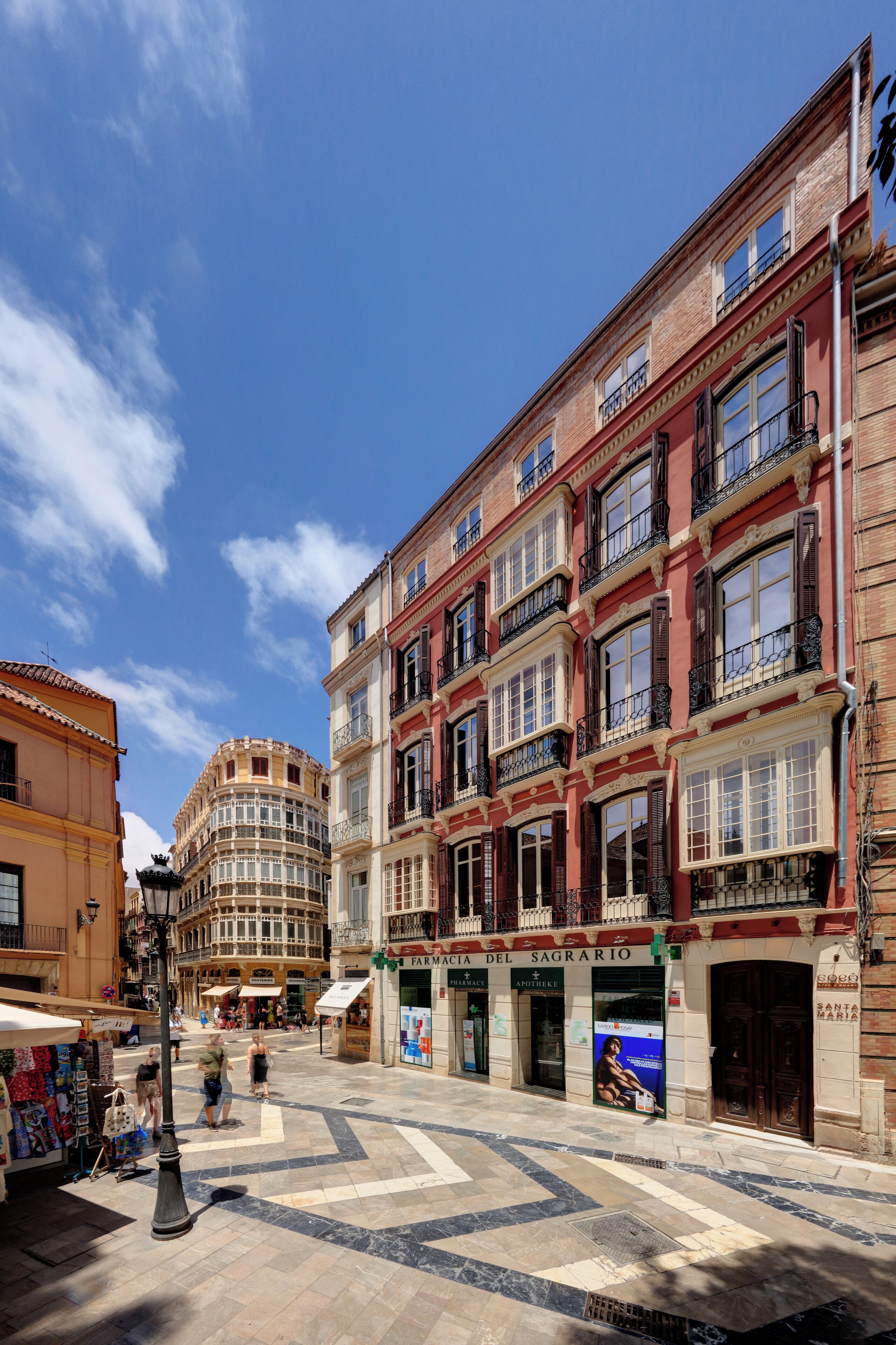 Una calle con edificios históricos, incluyendo una farmacia y una tienda con un letrero que dice 'SANTA MARIA'.