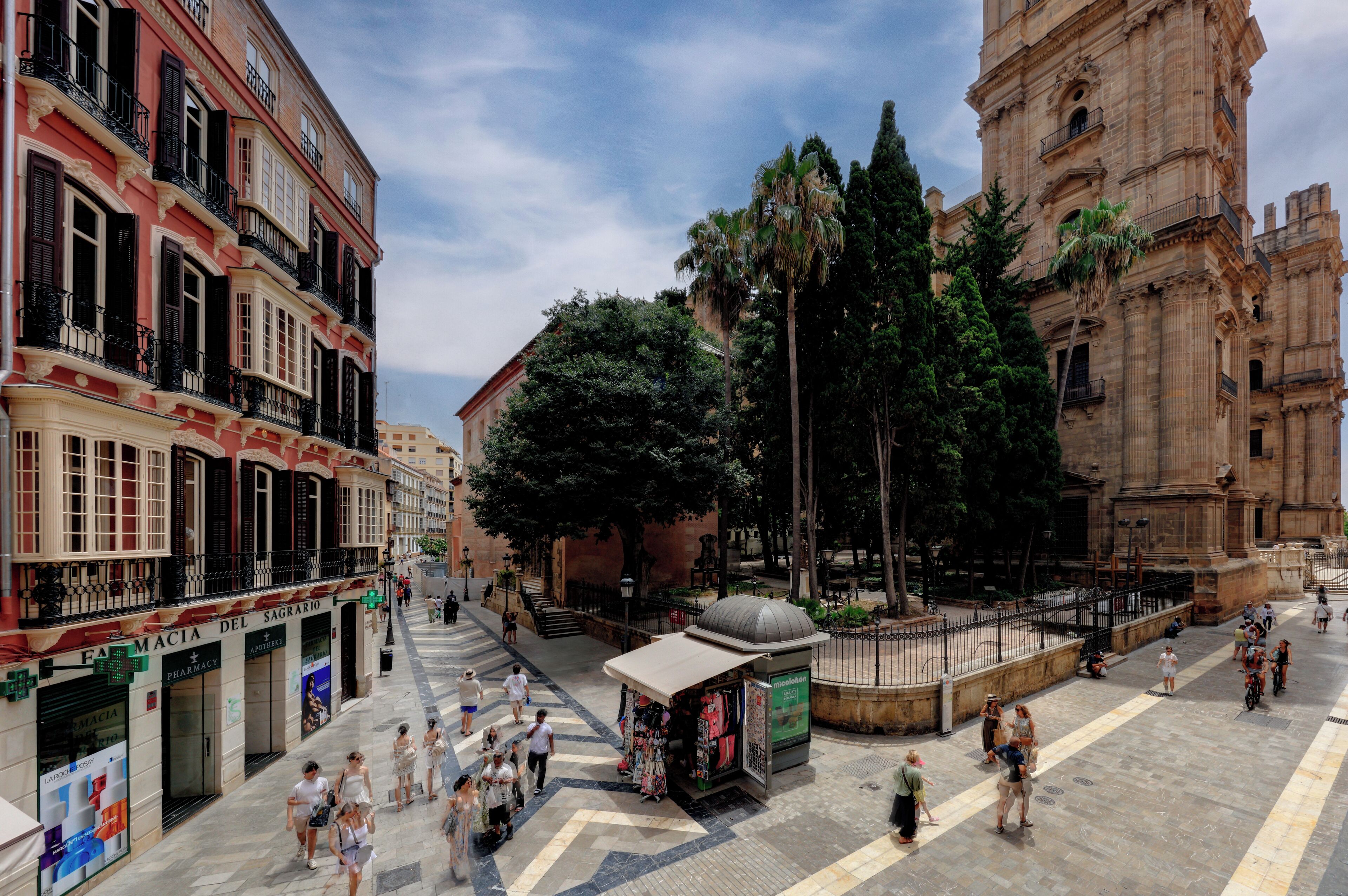 A plaza with a historic building, a pharmacy, and a kiosk.