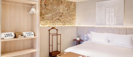 Een hotelkamer met een groot bed, een houten kledingkast, een kleine tafel met een tijdschrift en een decoratieve wand.
