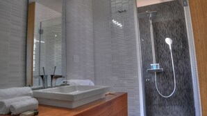 A modern bathroom with a large mirror, a rectangular sink, and a walk-in shower with a glass door. - Oceanfront 1BR en Ultravioleta Cabarete. Wifi Rápido, Balcón & Parking (Cabarete)