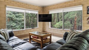 Ein Wohnzimmer mit einem großen Fernseher an der Wand, einem Holztisch und einer Couch.