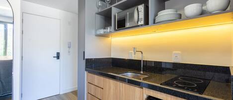 Una cocina moderna con microondas integrado, un lavamanos y una encimera negra.