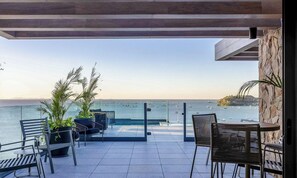 A terrace with seating and potted plants, overlooking a body of water with boats. - Studios in a Seaside Building, Close to Beto Carreiro at Penha Spot - Psob (Penha)
