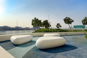 Une terrasse sur le toit, dotée de mobilier blanc et moderne, offrant une vue sur le paysage urbain.