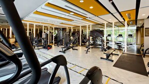 Ein Fitnessstudio mit Trainingsgeräten, Spiegeln und einem großen Fenster.
