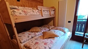 A bunk bed with floral bedding in a room with wooden floors and a balcony.