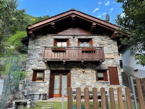 A stone building with a wooden balcony, a wooden fence, and a stone wall.