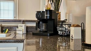A kitchen with a coffee maker, a sponge, and a soap dispenser.