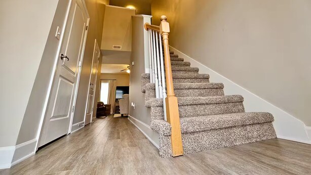 A staircase with wooden handrails and carpeted steps leading to a landing.
