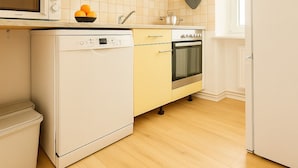 Eine kleine Küche mit Mikrowelle, Geschirrspüler, Backofen und einem kleinen Arbeitsplatz mit einer Orangenschale.