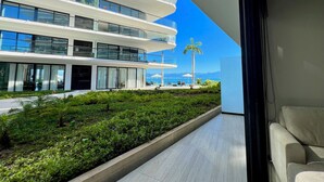 A modern hotel with a multi-level structure, outdoor seating area, and a view of the ocean.