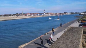 Una passeggiata costiera con cielo sereno, un faro e un mare calmo.