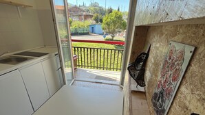 Una cucina con vista su un balcone, un piccolo edificio blu e una recinzione.