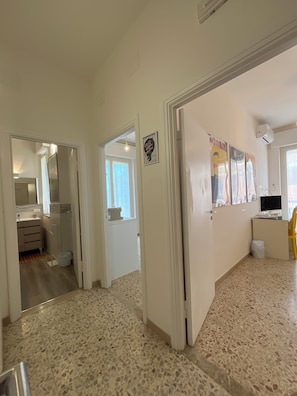 A hallway with a tiled floor, a door leading to a bathroom, and a wall with a framed picture. - GUEST HOUSE ACCOMMODATION MATILDE SPRING (Terni)