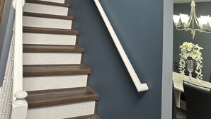 A staircase with white balusters and wooden steps leading to a landing. There are two paintings of tulips on the wall above the staircase. - Charming 4-bedroom house with WiFi, AC in wonderful Scotrun (Scotrun)