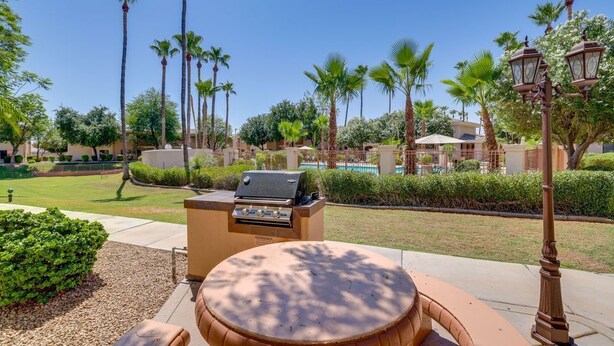 An outdoor patio with a grill, seating, and palm trees. - Modern Condo Near Stadiums & Westgate Fun (Phoenix)