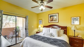A bedroom with a bed, a ceiling fan, a nightstand, a lamp, and a sliding glass door leading to an outdoor area. - Modern Condo Near Stadiums & Westgate Fun (Phoenix)