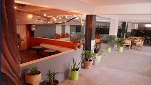 Un espace intérieur spacieux comprenant un coin salon, plusieurs tables et des plantes en pot.