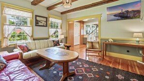 A cozy living room with a sofa, a coffee table, and a rug. There is a staircase leading to another room.