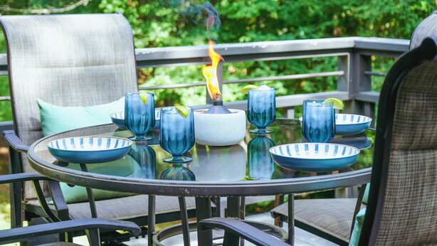 A round glass table with blue and white striped bowls, a white candle holder, and blue glassware. - 5 Minutes To Dollywood - Cottage With Fire Pit, Coffee Bar & Private Deck (Pigeon Forge)