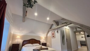 Una camera da letto con un letto, comodini, una pianta pensile, uno specchio e una porta che dà su un'altra stanza.