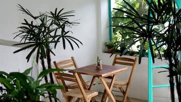 Una mesa y sillas de madera en una habitación con plantas en macetas y un ventanal.