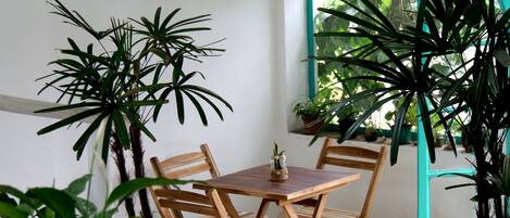 A wooden table and chairs in a room with potted plants and a window.