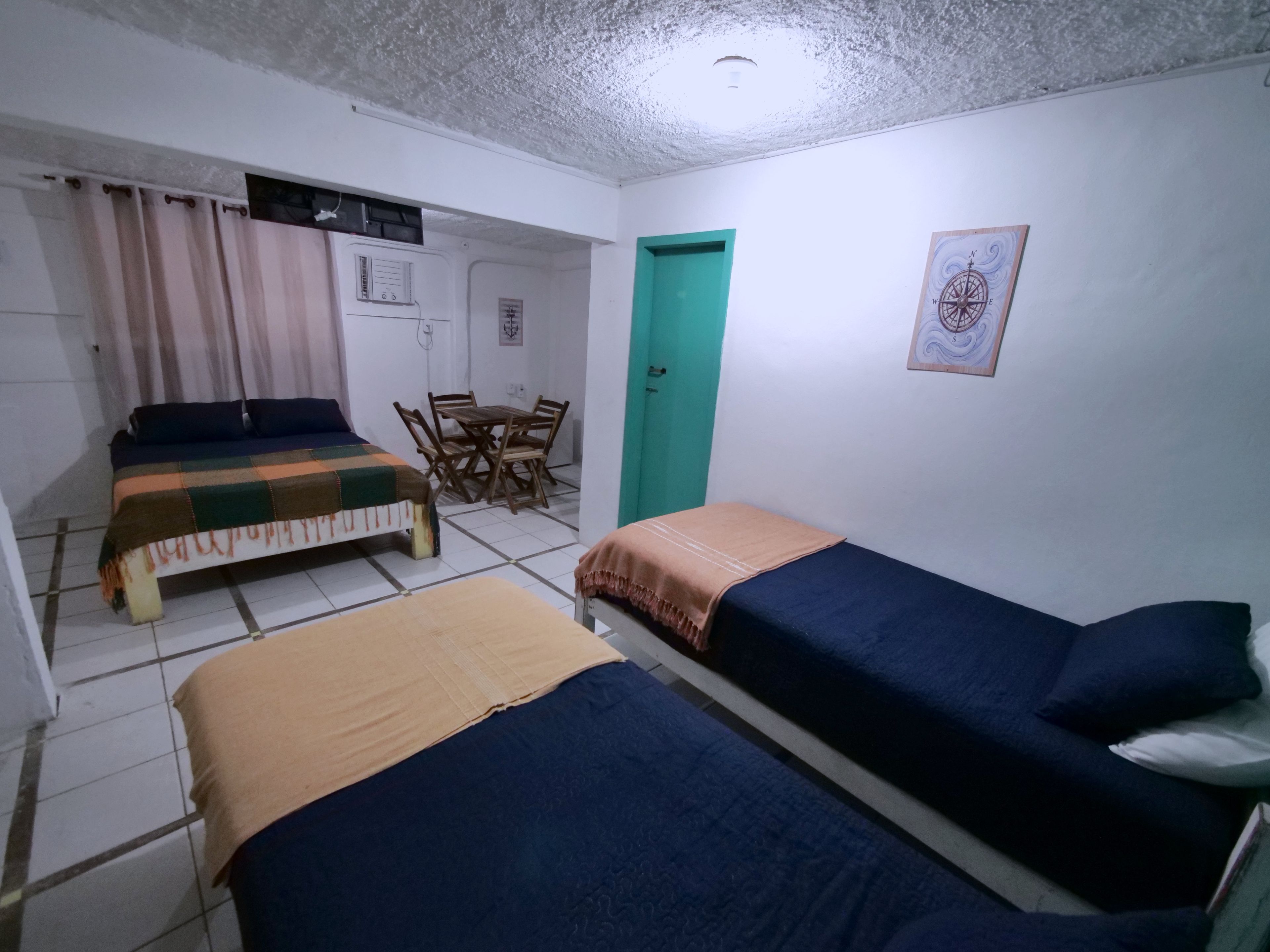 A room with two beds, a dining table, and a green door.