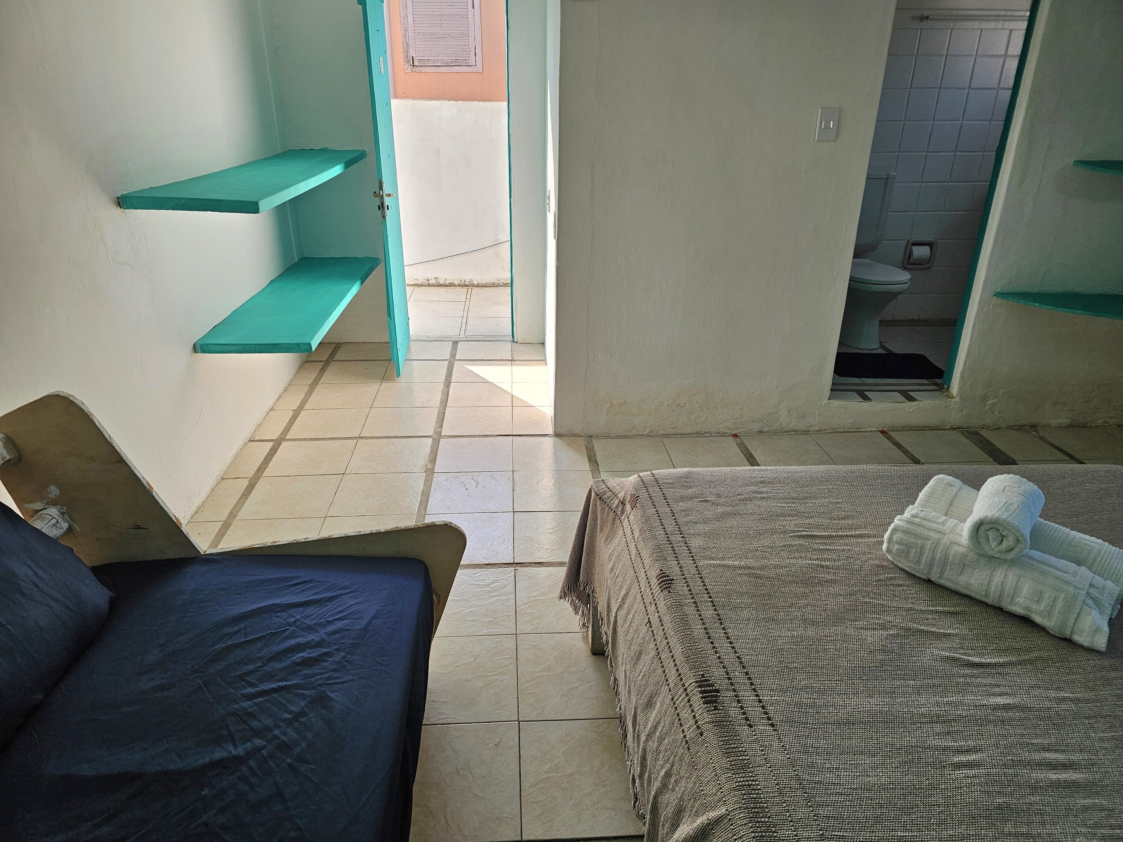 Une pièce comprenant un lit, une petite table et une salle de bain visible à travers une porte ouverte.
