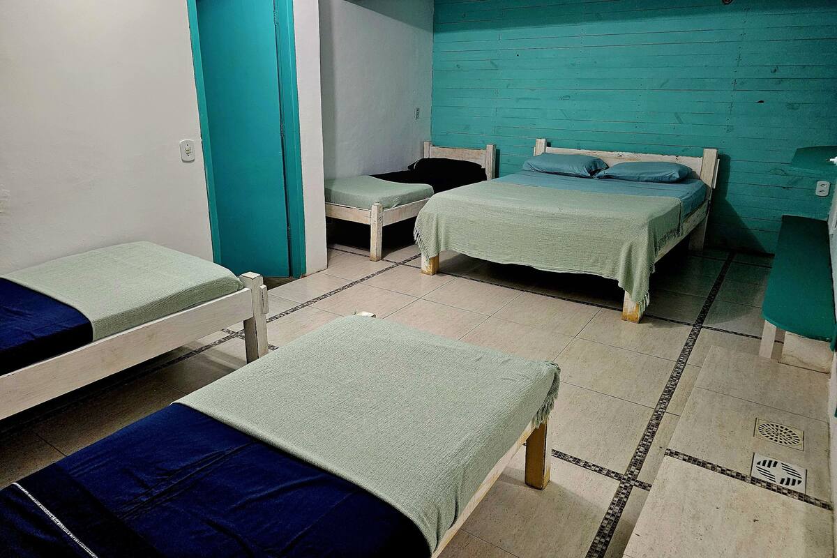 Ein Schlafsaalzimmer mit zwei Einzelbetten, einem kleinen Tisch und einer türkisblauen Wand.
