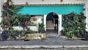 A building with a turquoise awning, a visible entrance, and potted plants around the entrance. - Pousada Canoa do Mar (Buzios)