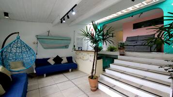 A living room with a blue sofa, a hanging chair, a staircase, and a potted plant.