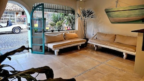 A cozy interior with a wooden bench, a potted plant, and a view of the street outside. - Pousada Canoa do Mar (Buzios)