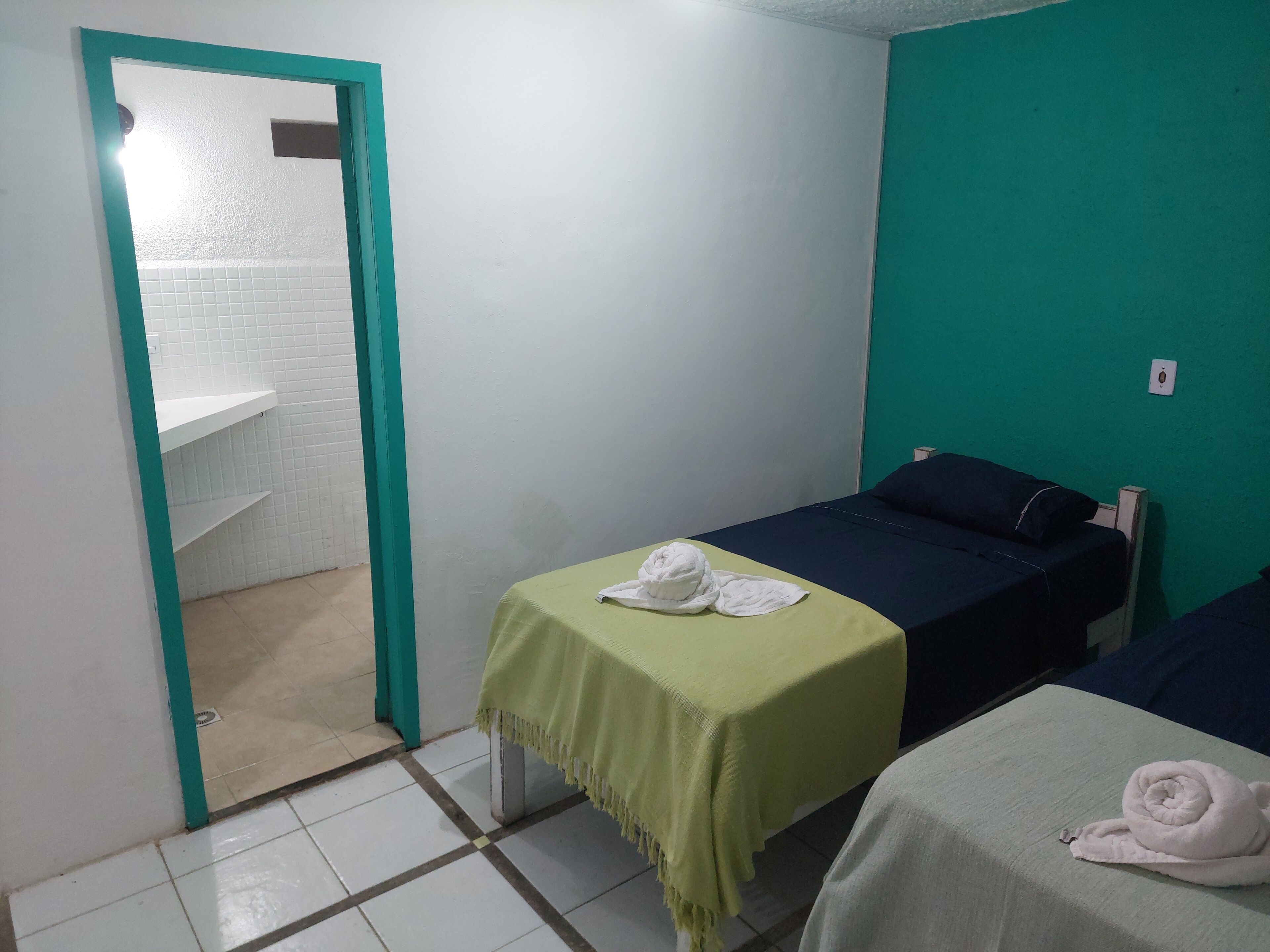 A small, clean room with a bed, a bedside table, and a green wall.