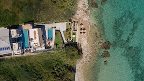 Vista aérea de un resort con varias piscinas, una zona de playa y un litoral rocoso.