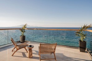 A balcony with two wicker chairs, a small round table, and two potted plants.