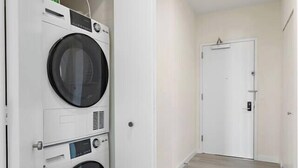 A laundry room with two stacked washing machines and a closed door in the background.