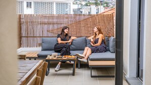 A modern outdoor seating area with a bamboo screen, a sofa, and a coffee table with snacks. - The Graceful Manor by Homie (Funchal)