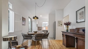 A modern kitchen with wooden flooring, a dining area with chairs, a central island, and a pendant light. - The Graceful Manor by Homie (Funchal)