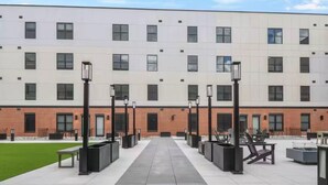 Il s’agit d’un bâtiment moderne doté d’une façade en briques et d’un toit plat. On y trouve des espaces extérieurs aménagés avec des tables et des chaises, ainsi qu’un chemin menant à l’entrée.