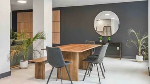 Un espace repas moderne avec une table et des chaises en bois, un grand miroir et des plantes en pot.