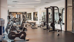 Un gimnasio moderno con varios equipos de ejercicio, incluyendo cintas de correr, máquinas de pesas y pesas libres.