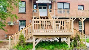 Ein Backsteinhaus mit einer Holzterrasse und einer Treppe, die zu einer Tür mit der Aufschrift "Riverside Legacy Building" führt.