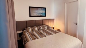 A bedroom with a bed, a nightstand, a framed picture on the wall, and a door. - Vita 1409 Centro SP Bom Retiro - Digital Check-in with Wi-Fi (Bom Retiro São Paulo)