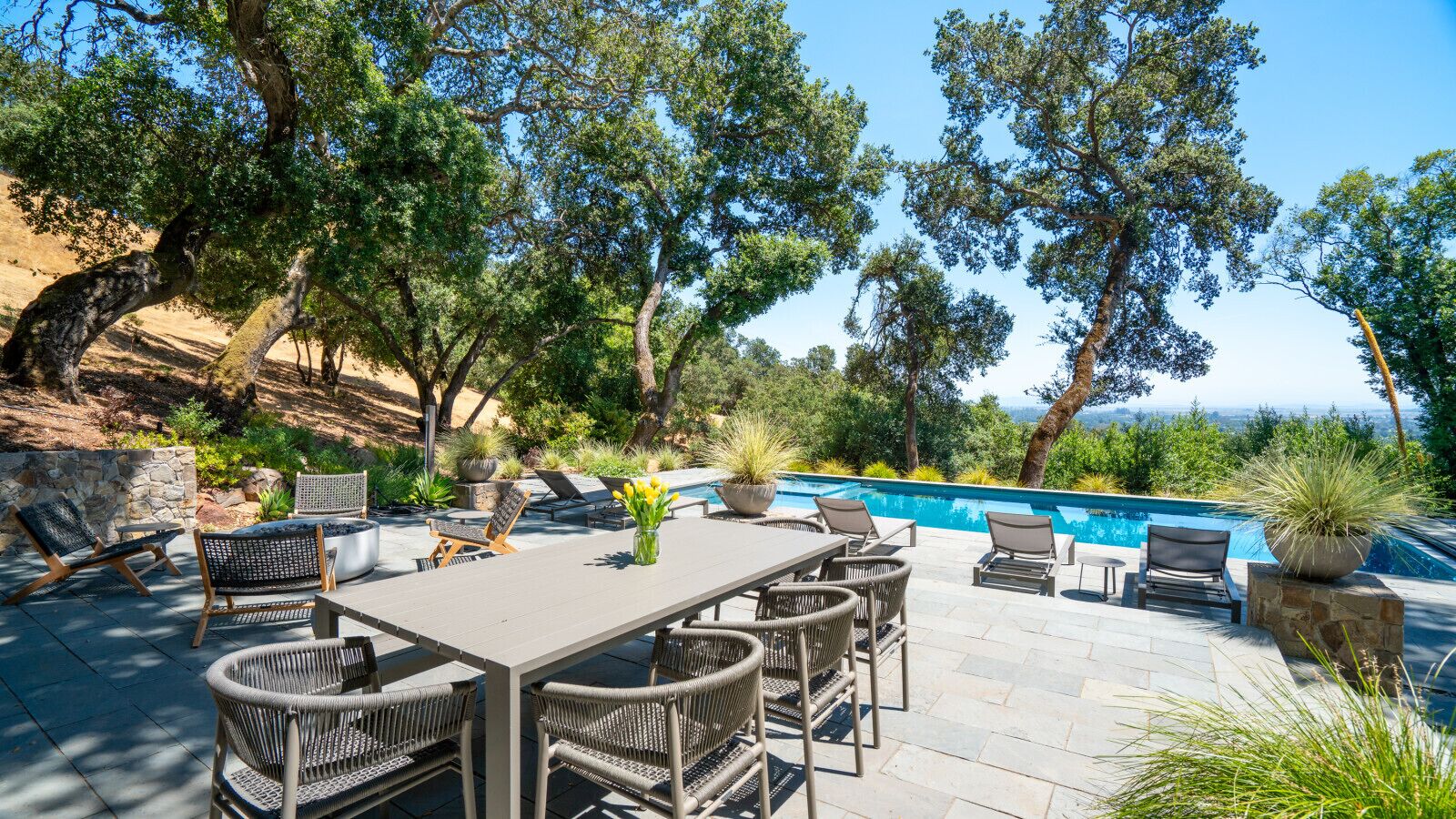 Un patio exterior con piscina, rodeado de árboles y amueblado con una mesa y sillas.