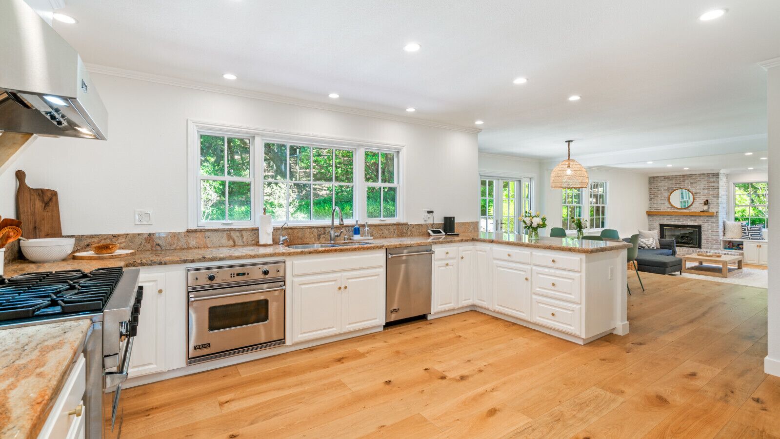 A spacious kitchen with white cabinetry, a large island, and a dining area with a fireplace.