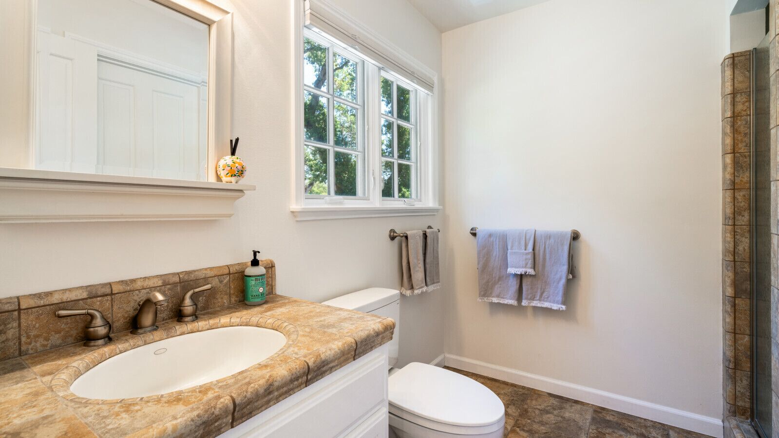 A bathroom with a large sink, a toilet, and a window.